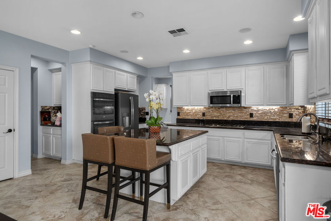 18080 Tanzanite Road San Bernardino, CA 92407 - Photo 15 of 49 a kitchen with stainless steel appliances kitchen island granite countertop a stove a sink a refrigerator and white cabinets