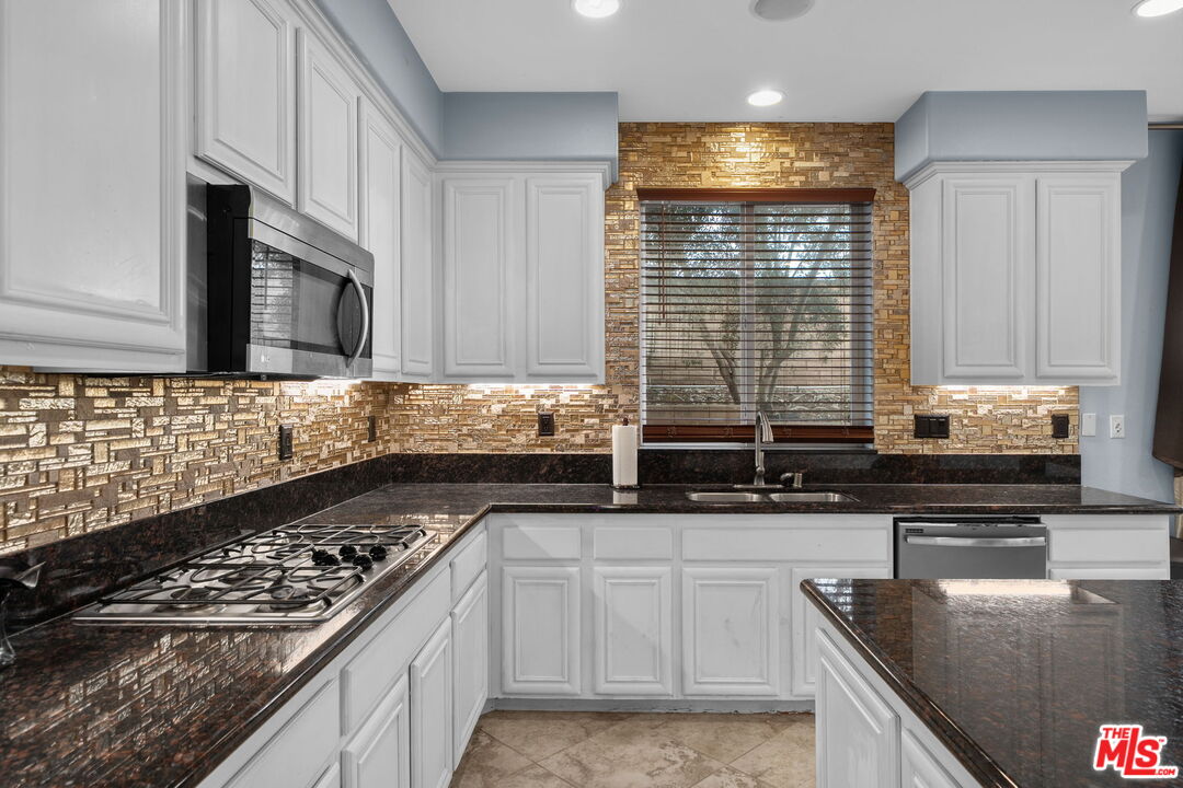 18080 Tanzanite Road San Bernardino, CA 92407 - Photo 17 of 49 a kitchen with stainless steel appliances granite countertop a sink stove and cabinets