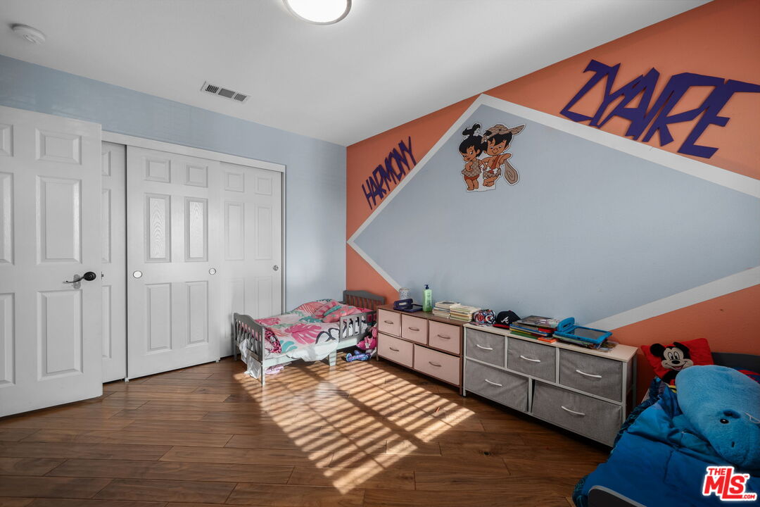 18080 Tanzanite Road San Bernardino, CA 92407 - Photo 31 of 49 a bedroom with baby crib and wooden floor