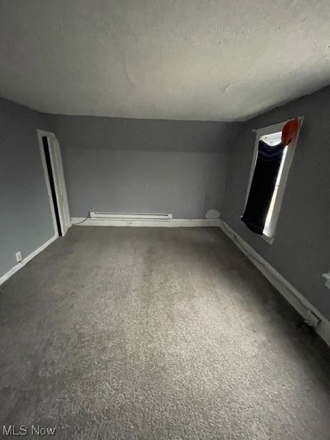 10210 Reno Avenue Cleveland, OH 44105 - Photo 15 of 26 Spare room featuring dark carpet, a baseboard heating unit, and a textured ceiling
