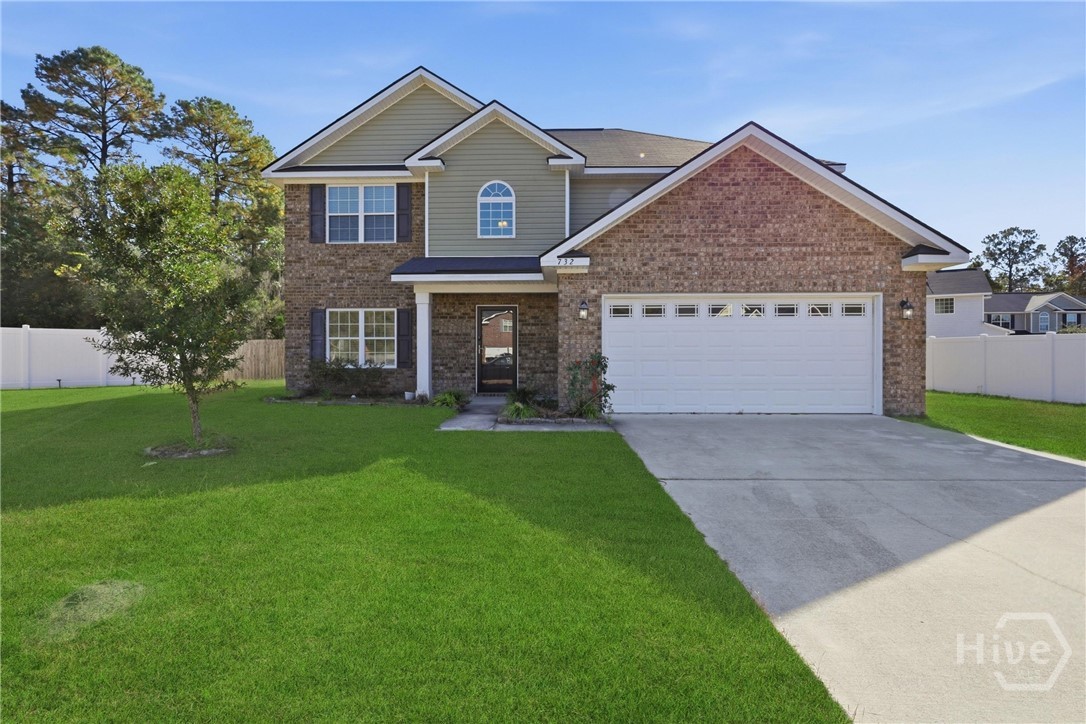 Two-story home with brick and siding exterior, covered front entry, two-car garage, wide driveway, and a large green lawn.