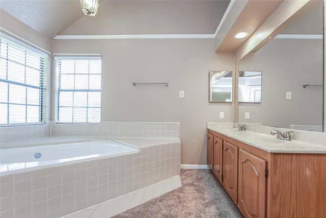 a spacious bathroom with a tub sink and mirror