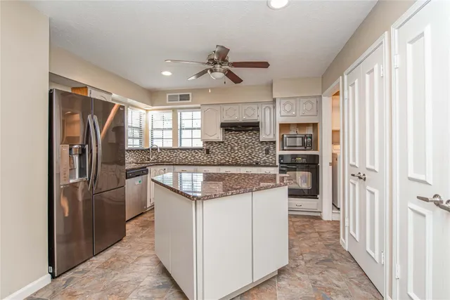 a kitchen with stainless steel appliances granite countertop a refrigerator and a sink