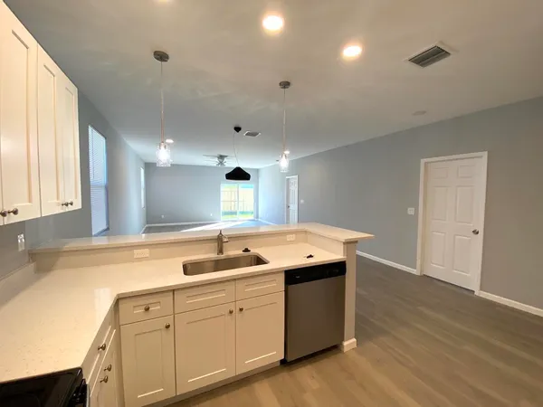 a kitchen with granite countertop a sink and dishwasher with wooden floor