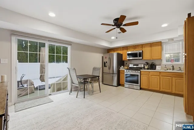 a kitchen with a refrigerator a stove top oven a sink dishwasher a dining table and chairs with wooden floor