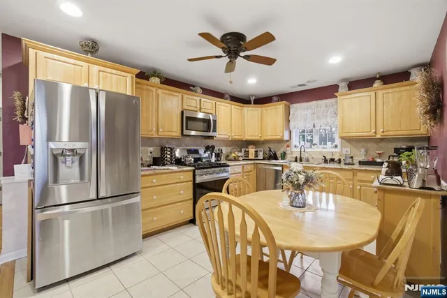 a kitchen with stainless steel appliances granite countertop a refrigerator a stove a sink dishwasher a dining table and chairs with wooden floor