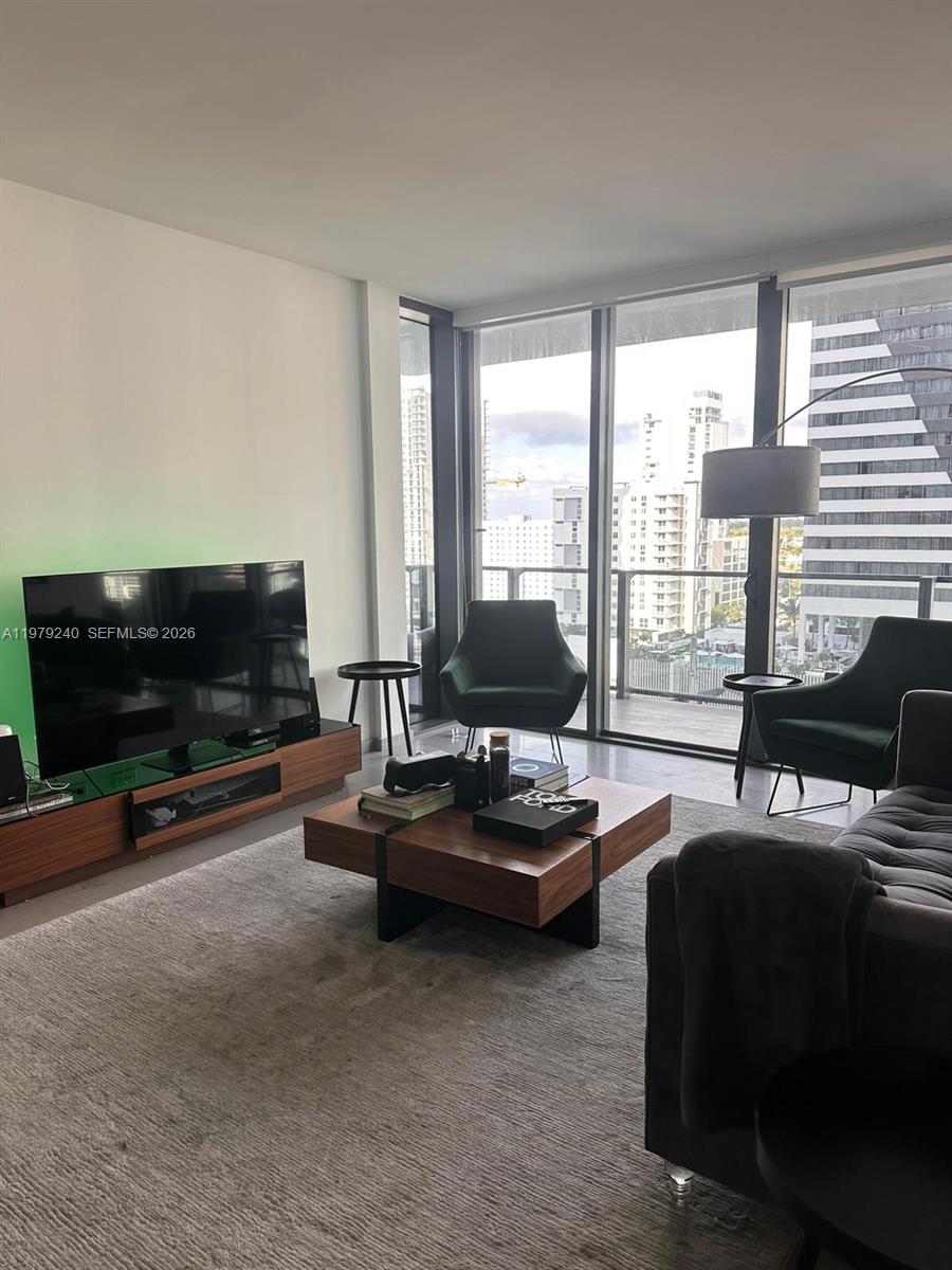 88 Southwest 7th Street, Unit 810 Miami, FL 33130 - Photo 3 of 10 a living room with furniture a flat screen tv and a large window