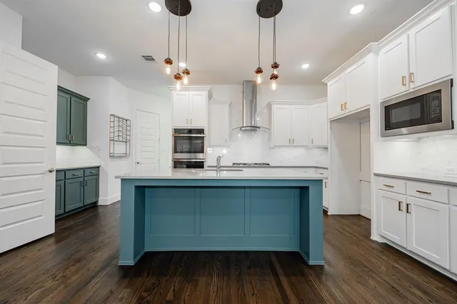 a kitchen with stainless steel appliances granite countertop a sink a stove and a wooden floors