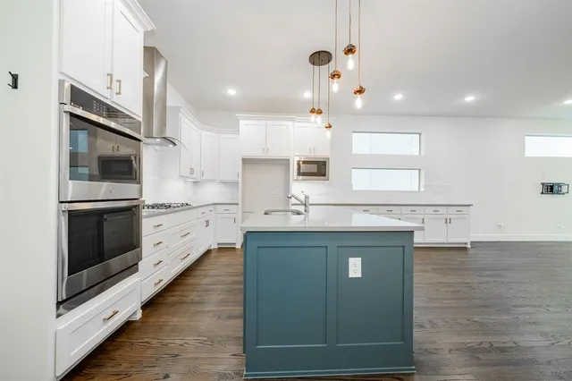 a kitchen with stainless steel appliances granite countertop a sink a stove and a refrigerator