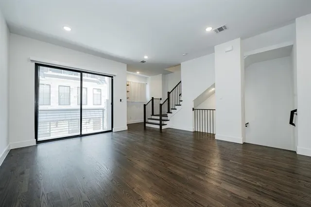 a view of an empty room with wooden floor and stairs