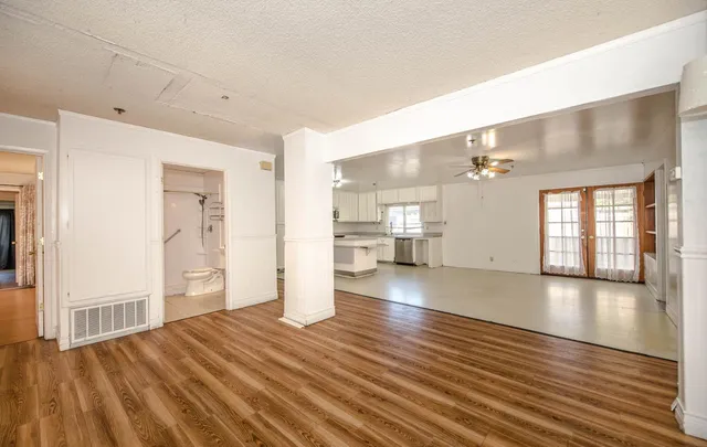 a view of an empty room with wooden floor and a window