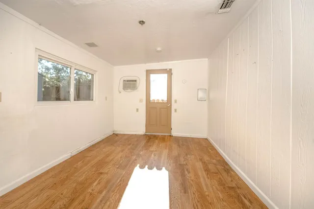 a view of empty room with wooden floor and fan