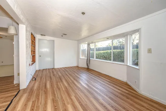 a view of a big room with wooden floor and windows