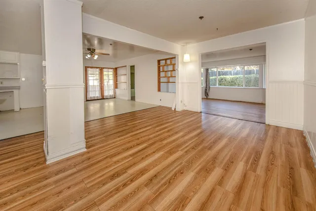 an empty room with wooden floor and windows