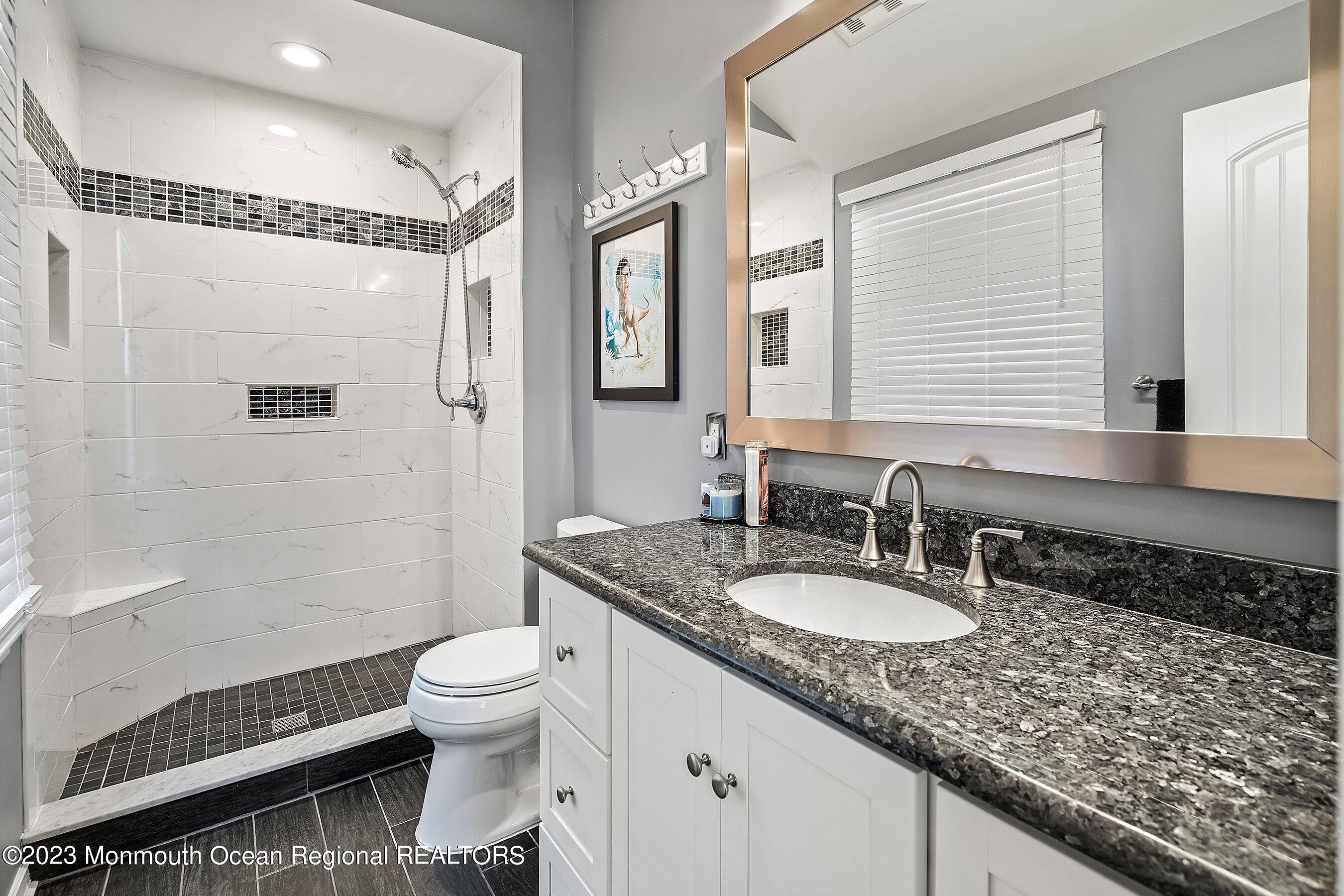 3 Adams Court Howell, NJ 07731 - Photo 24 of 36 a bathroom with a granite countertop sink a toilet a mirror and shower
