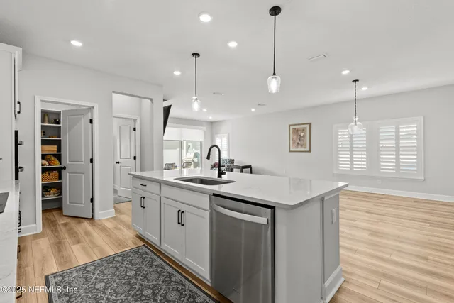 a kitchen with stainless steel appliances granite countertop a sink a window and wooden floor