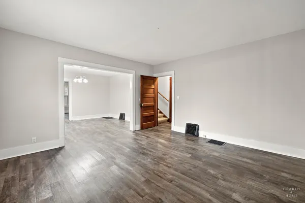 a view of an empty room with wooden floor closet and a window