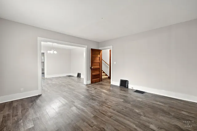 a view of an empty room with wooden floor closet and a window