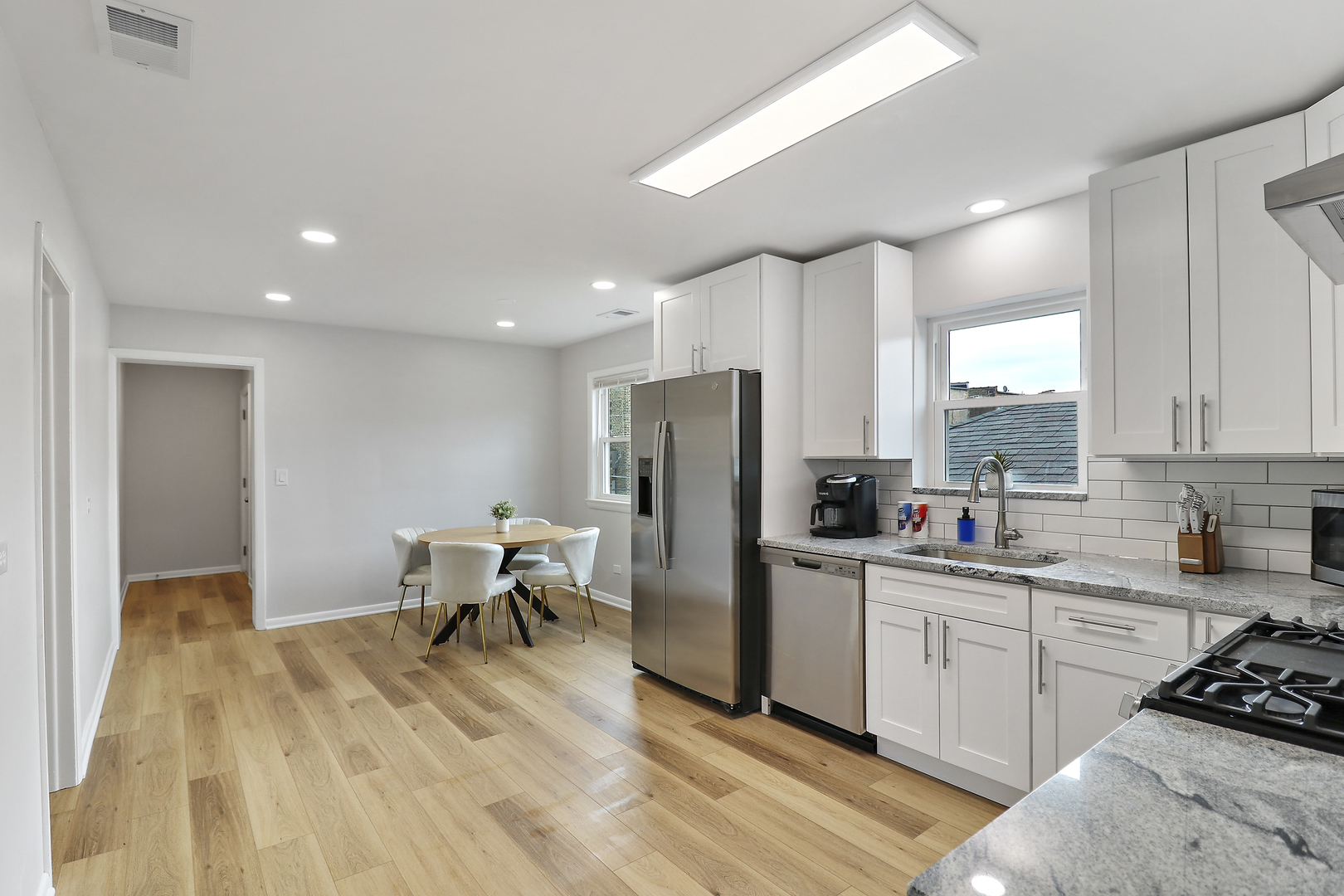 135 Custer Avenue, Unit 3 Evanston, IL 60202 - Photo 5 of 18 a kitchen with stainless steel appliances kitchen island granite countertop a sink cabinets and wooden floor