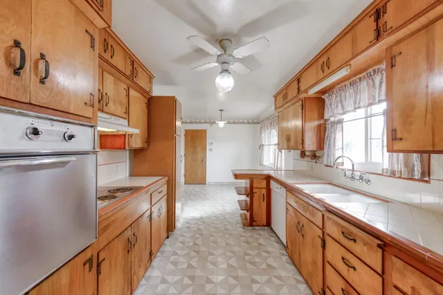 a kitchen with stainless steel appliances a sink dishwasher a refrigerator and a stove with wooden floor