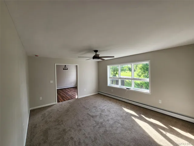 an empty room with windows and chandelier fan