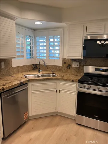 a kitchen with granite countertop cabinets stainless steel appliances and a sink