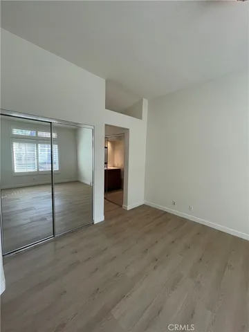 a view of an empty room with wooden floor and closet