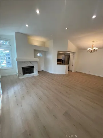 an empty room with wooden floor fireplace and windows
