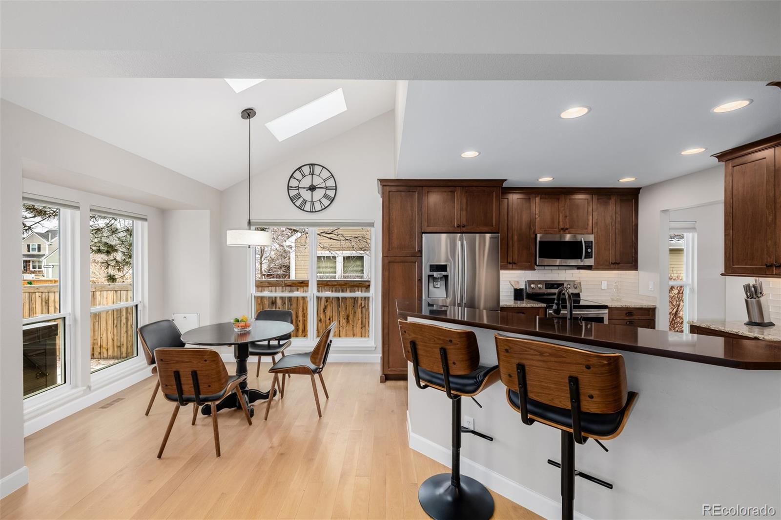8827 South Cactus Flower Way Highlands Ranch, CO 80126 - Photo 12 of 49 a kitchen with stainless steel appliances kitchen island granite countertop a stove a refrigerator a sink a dining table and chairs with wooden floor