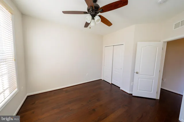 an empty room with wooden floor ceiling fan and windows