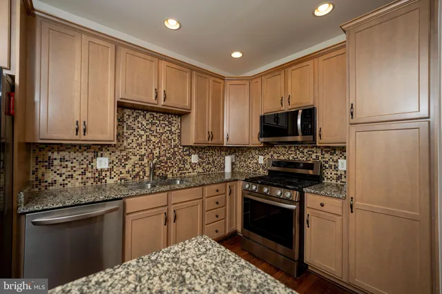 a kitchen with stainless steel appliances granite countertop a stove a refrigerator and a microwave