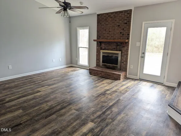 an empty room with wooden floor a fireplace and windows