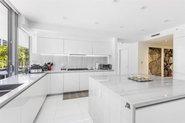 a kitchen with granite countertop a sink and white cabinets