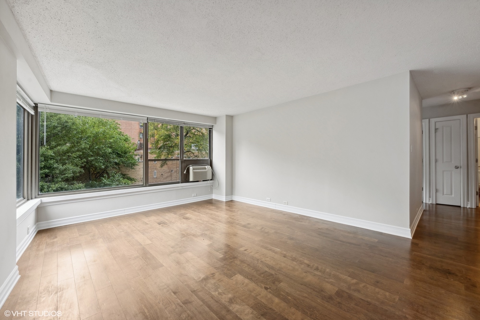 2930 North Sheridan Road, Unit 301 Chicago, IL 60657 - Photo 6 of 20 a view of an empty room with wooden floor and a window