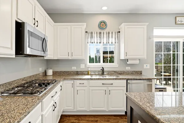 a kitchen with stainless steel appliances granite countertop a stove a sink and a microwave
