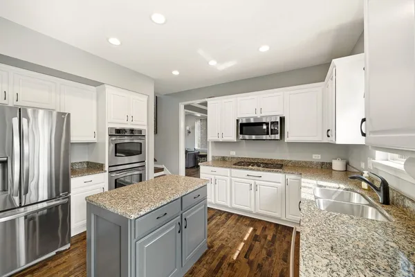 a kitchen with stainless steel appliances granite countertop a sink stove microwave and refrigerator