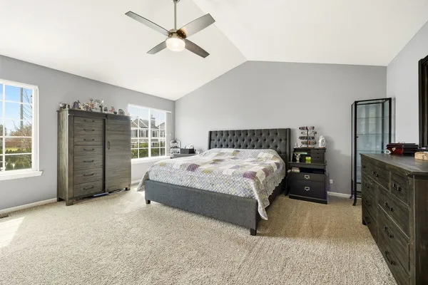 a spacious bedroom with a bed a dresser and a large mirror