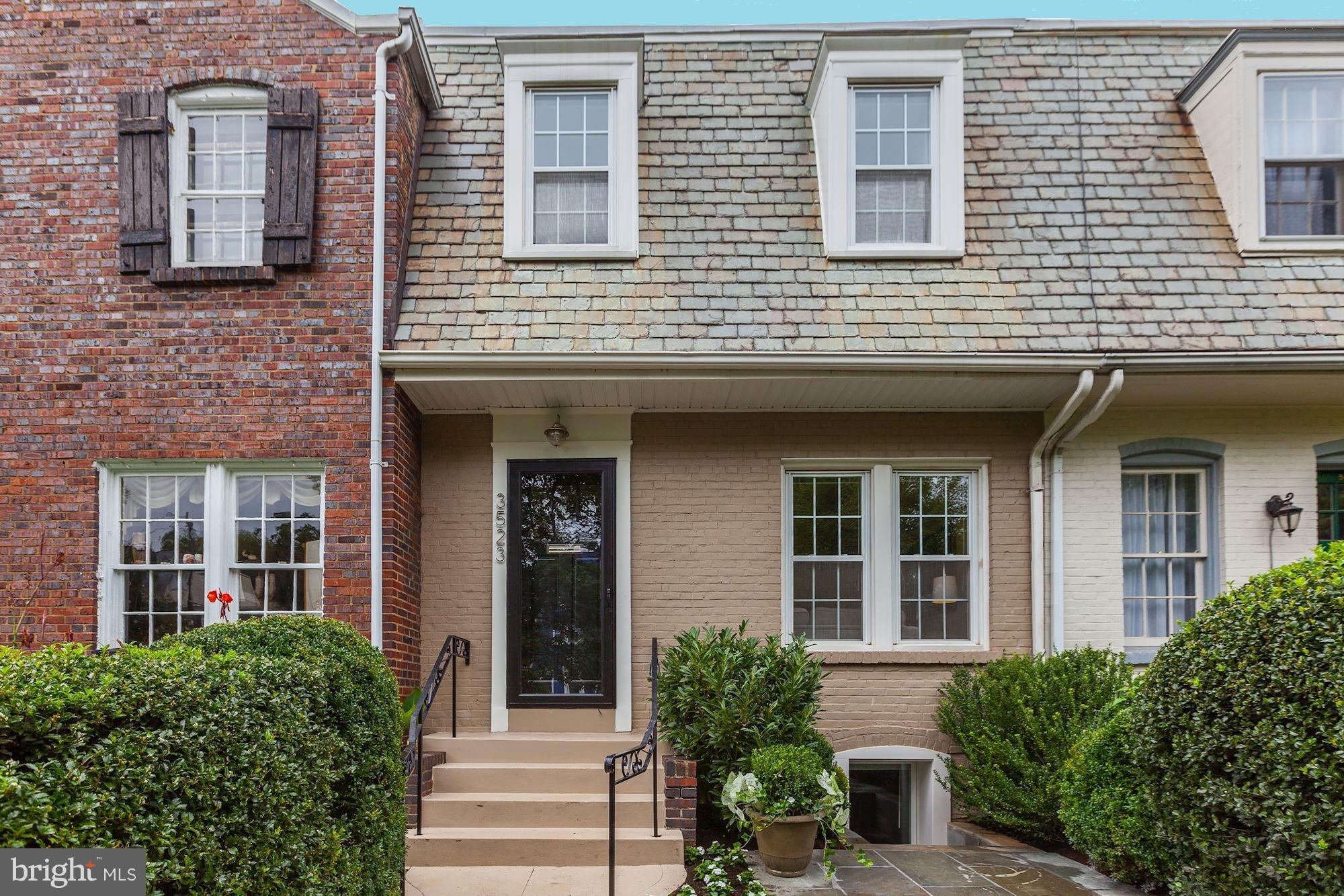 a view of a brick house with a large windows and flower plants