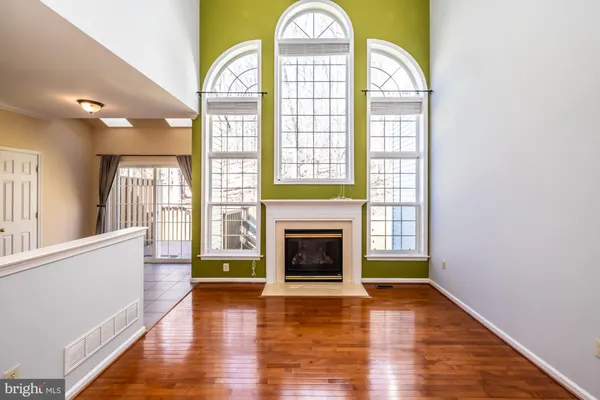 a view of an empty room with wooden floor fireplace and a window