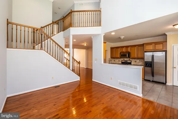 a view of a hallway with wooden floor and a kitchen
