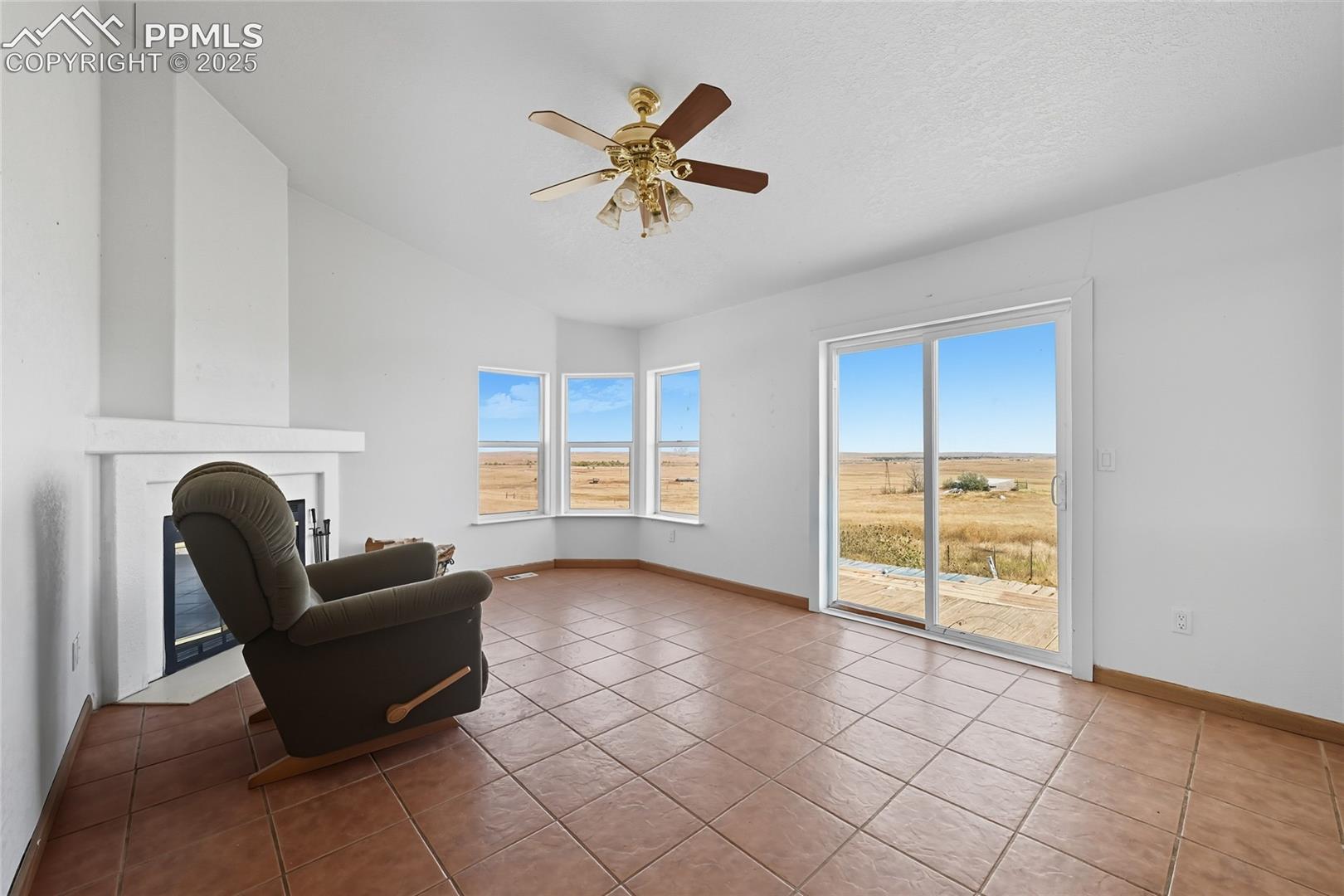 16595 North Yoder Road Calhan, CO 80808 - Photo 17 of 28 Sitting room with lofted ceiling, tile patterned floors, ceiling fan, a textured ceiling, and a fireplace