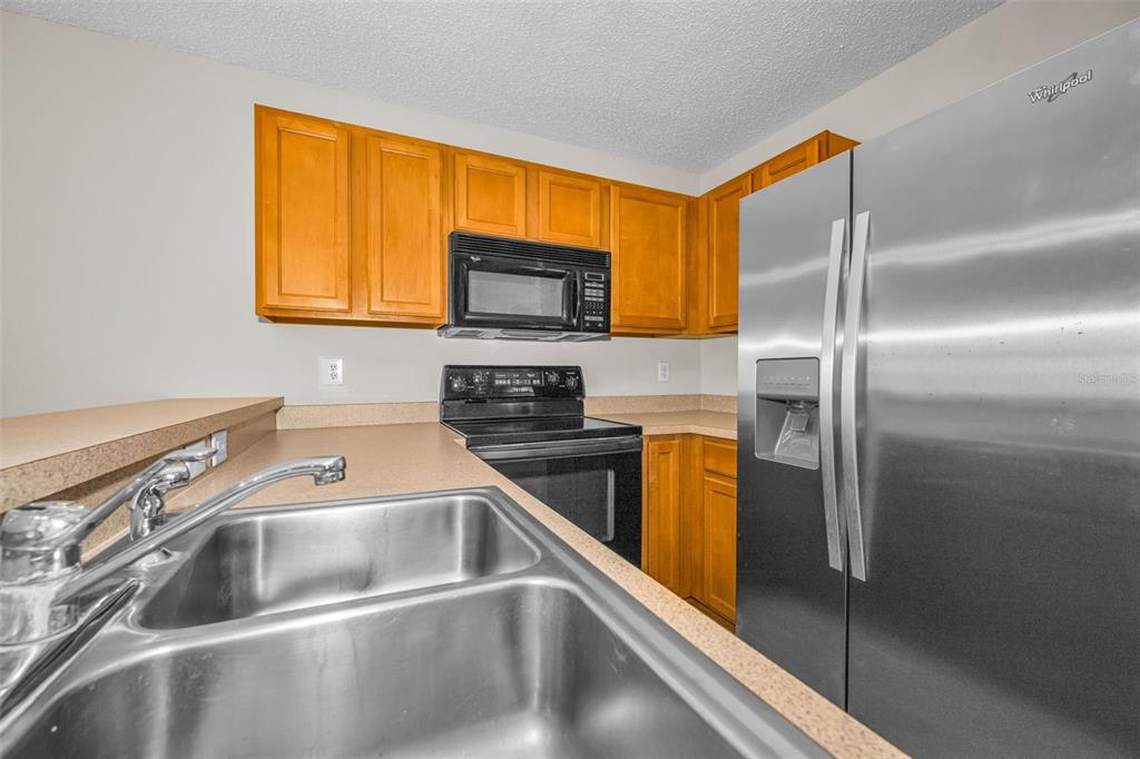 8015 Savannah Sunset Lane Tampa, FL 33615 - Photo 12 of 35 a kitchen with a sink a microwave a refrigerator and a stove top oven