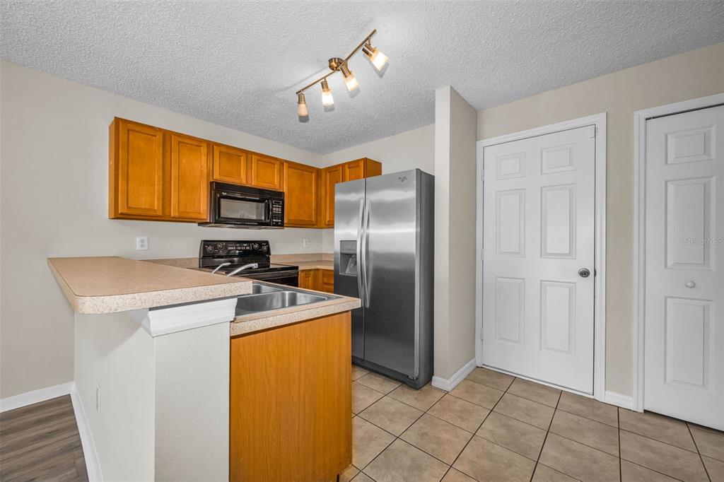 8015 Savannah Sunset Lane Tampa, FL 33615 - Photo 10 of 35 a kitchen with a refrigerator a stove a washer dryer and cabinets