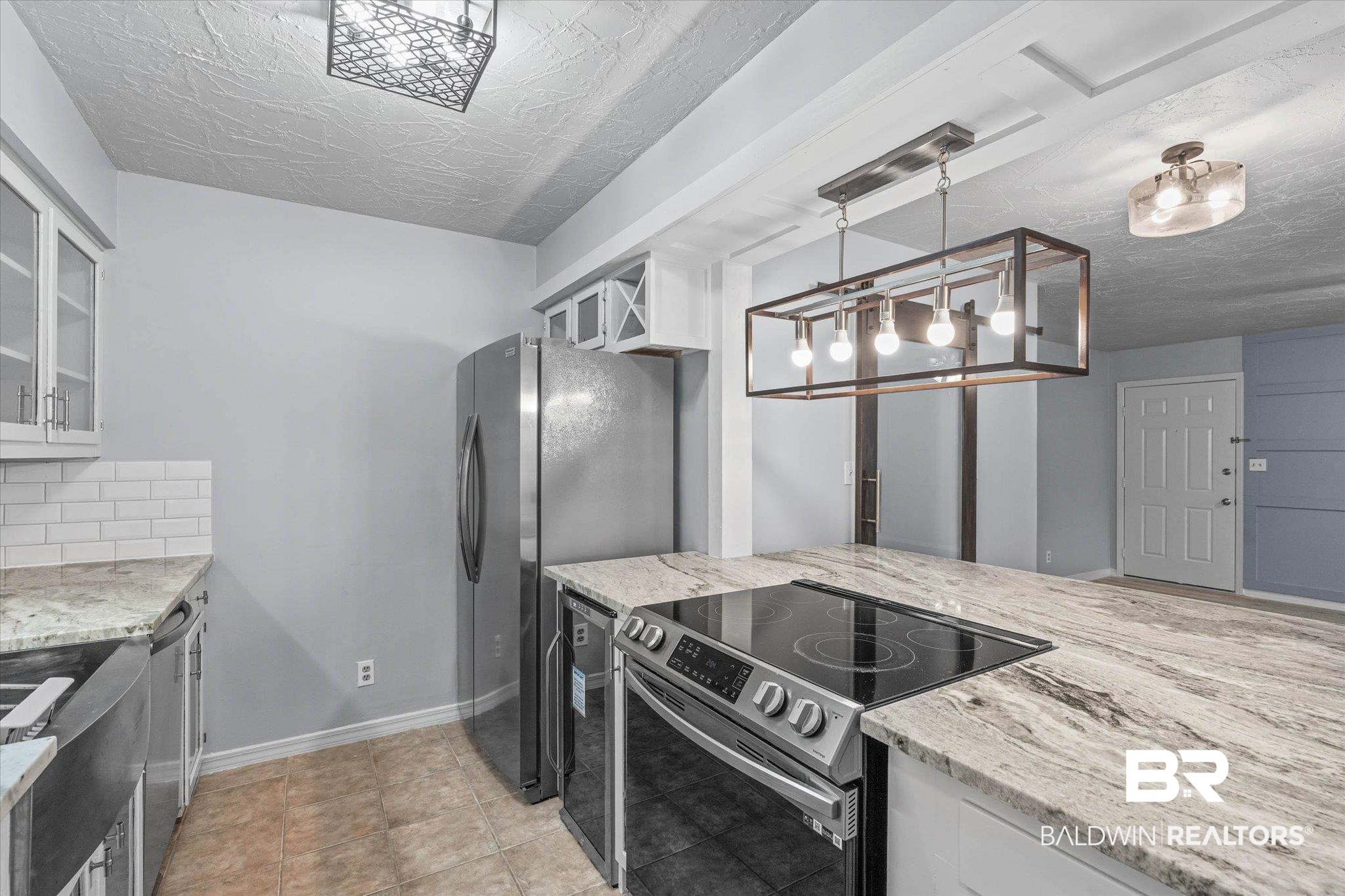 500 Grant Street, Unit C210 Daphne, AL 36526 - Photo 11 of 26 Kitchen featuring an integrated electric cooktop, white subway tile backsplash, stainless steel appliances, white cabinetry, and light-toned countertops