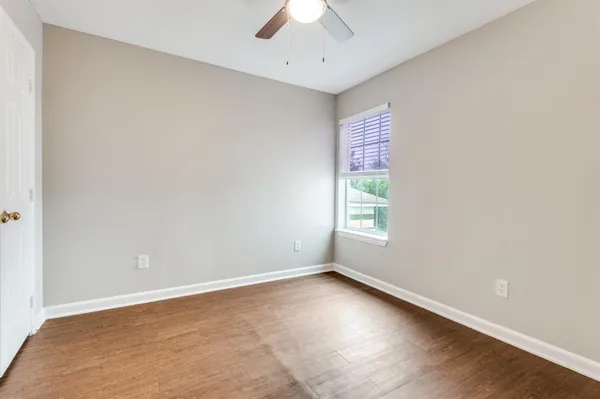 an empty room with a window and a ceiling fan