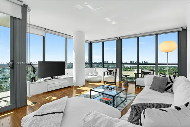 a view of a living room with furniture and floor to ceiling windows