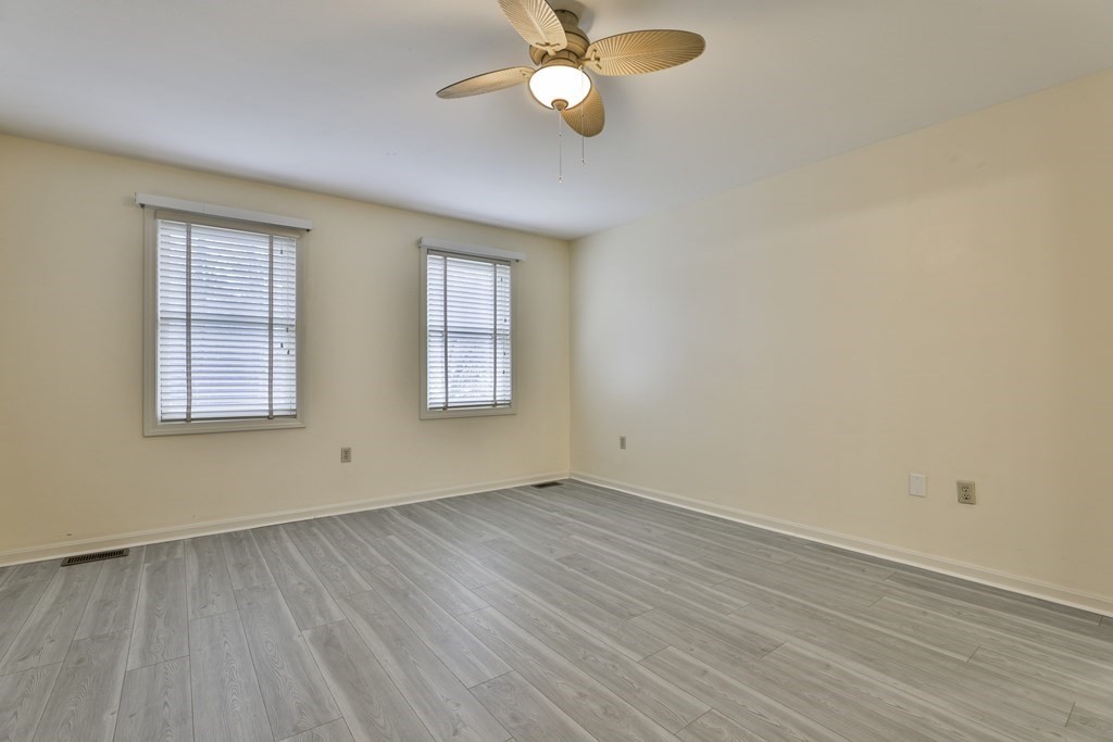 40 Mallard Point Road Merrimack, NH 03054 - Photo 23 of 40 an empty room with wooden floor chandelier fan and windows