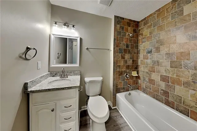 a bathroom with a granite countertop toilet sink and mirror