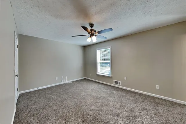 an empty room with windows and ceiling fan