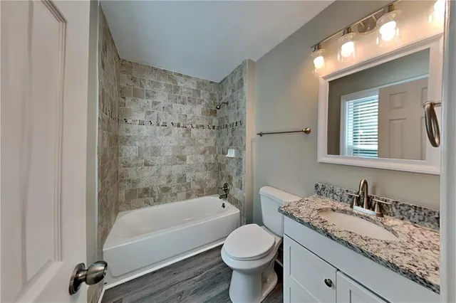 a bathroom with a granite countertop sink a toilet and bathtub